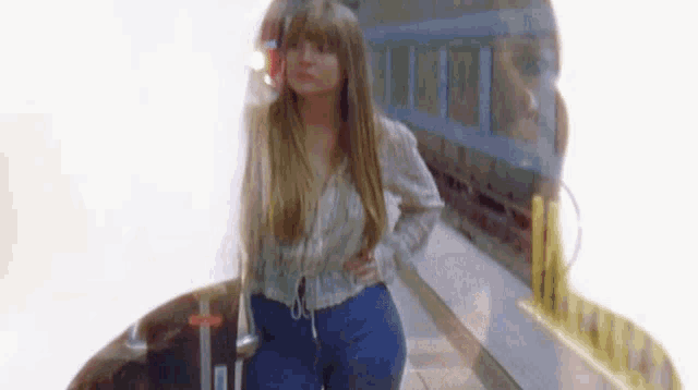 a woman is standing on a train platform with her hands on her hips and a train in the background .