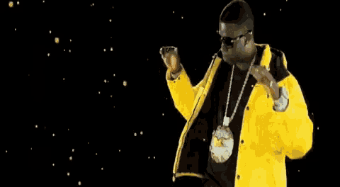 a man wearing a yellow jacket and sunglasses is dancing .