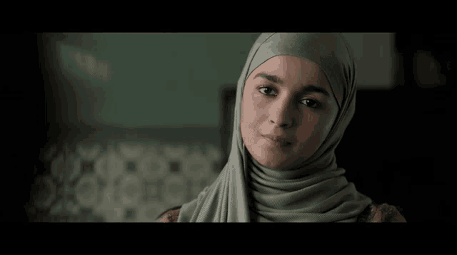 a woman wearing a hijab is smiling in a dark room
