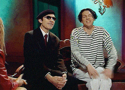 a man in a striped shirt is sitting next to another man in a suit