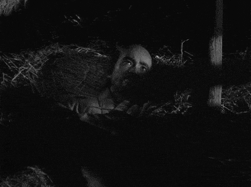 a man in a striped shirt is standing in a dark room