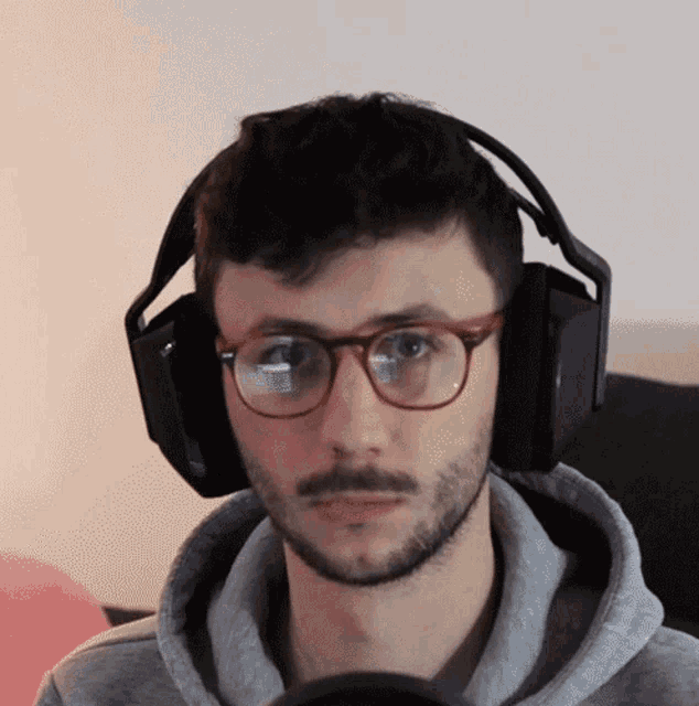 a man wearing glasses and headphones has a beard