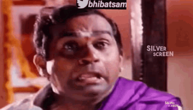 a man in a purple shirt is making a face .
