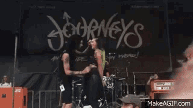 a couple kissing on stage in front of a sign that says journey 's