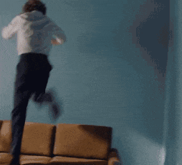 a man in a white shirt is kneeling down on a couch