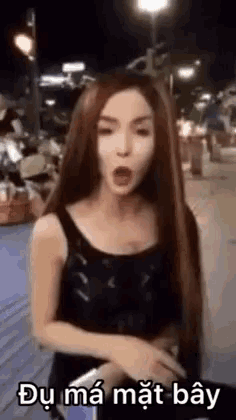 a woman with long red hair is standing on a sidewalk with her mouth open and a sign that says `` du ma mat bay '' .