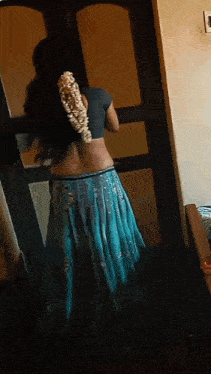 a woman in a blue skirt is standing in a room