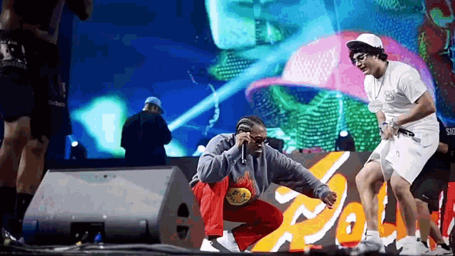 a man is kneeling down on a stage with a microphone in his hand