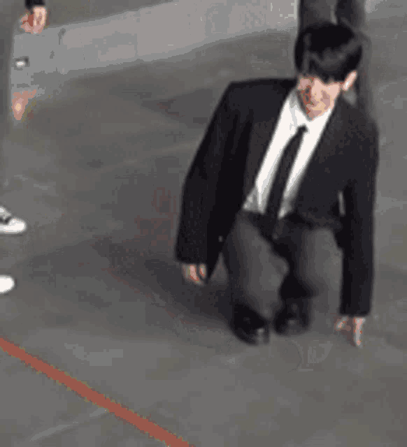 a man in a suit and tie is kneeling down on the floor