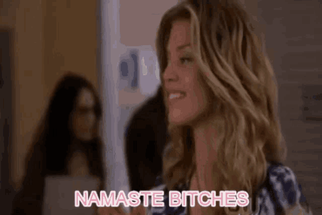 a woman is smiling and saying namaste bitches in a room