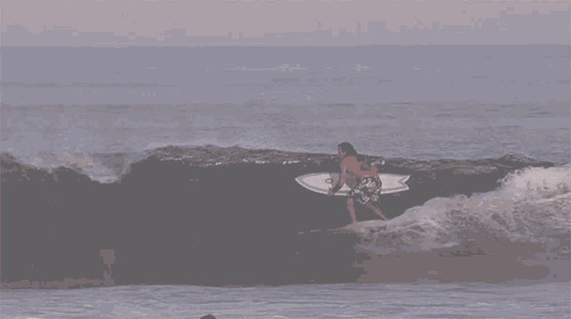a man is riding a wave on a surfboard while wearing a red shirt that says ' sd ' on it