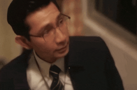 a man wearing glasses and a suit and tie is looking at the camera .
