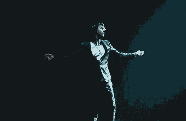 a man in a suit is dancing on a stage in the dark .