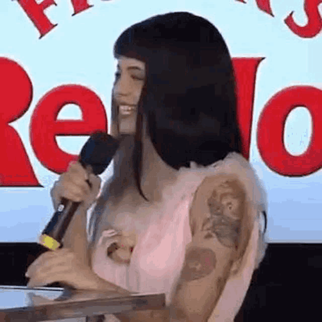 a woman is sitting at a table holding a microphone and smiling .