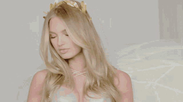 a woman with long blonde hair is wearing a gold crown on her head
