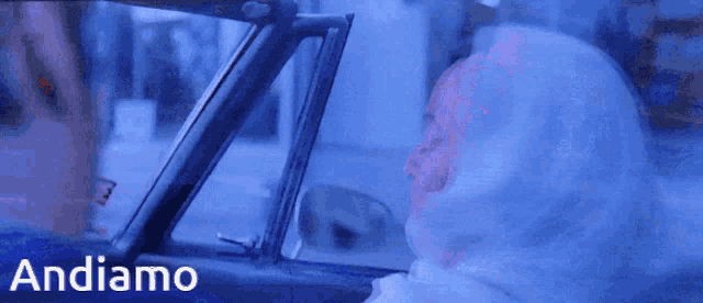 a woman in a white hoodie is driving a car and the word andiamo is on the bottom