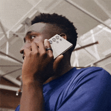 a man wearing a blue shirt talking on a cell phone