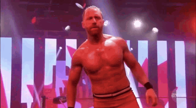 a man without a shirt is standing on a stage in front of a sign that says ' a ' on it .