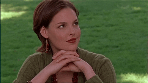 a woman sitting in the grass with her hands folded