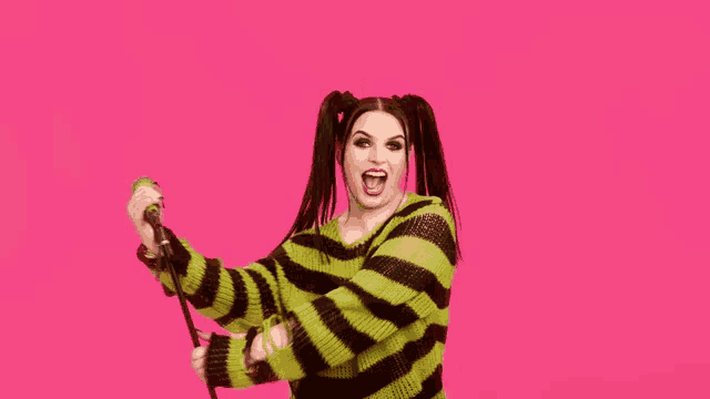 a woman in a striped sweater is singing into a microphone .