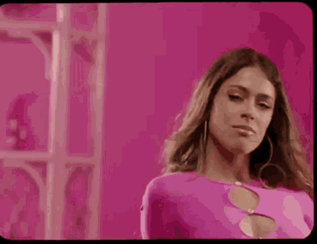 a woman in a purple dress is dancing in front of a pink background .