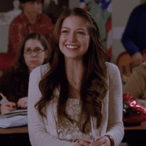 a woman is smiling in a classroom with a flag in the background