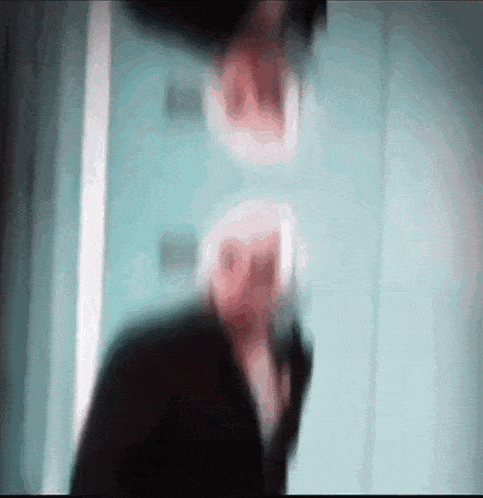 a blurry picture of a man talking on a phone with a reflection of him in the mirror