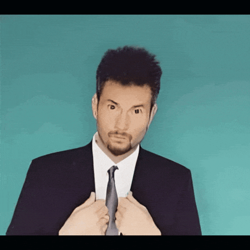 a man in a suit and tie adjusts his tie with his hands
