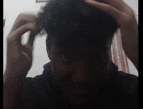a man is scratching his head with his hands while wearing a black shirt .