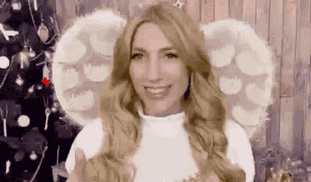 a woman wearing angel wings is giving a thumbs up .