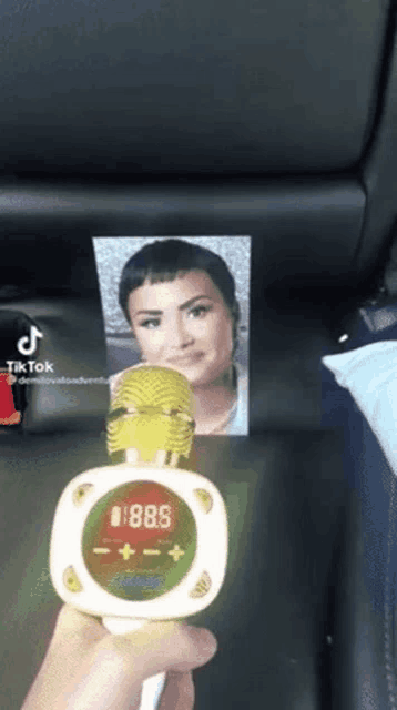 a person is holding a microphone with a picture of demi lovato on the back .