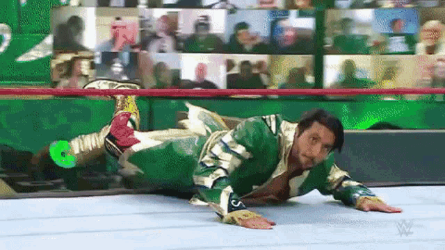 a wrestler is laying on his stomach in a wrestling ring .