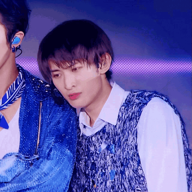 a man wearing a blue vest is standing next to another man wearing a blue jacket