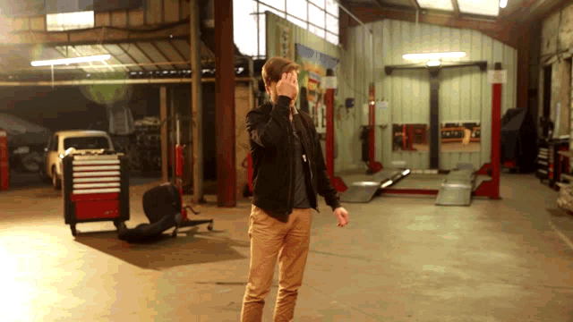 a man standing in a garage talking on a phone