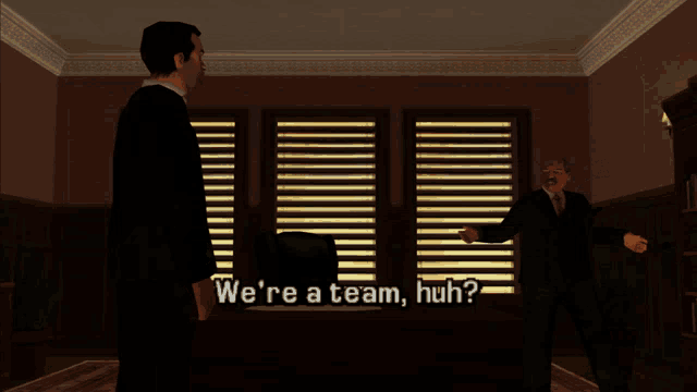 a man in a suit stands in front of a desk with the words we 're a team huh