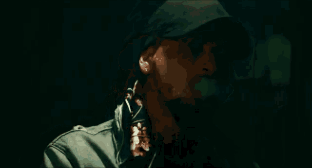 a man wearing a hat is smoking a cigarette with smoke coming out of his mouth