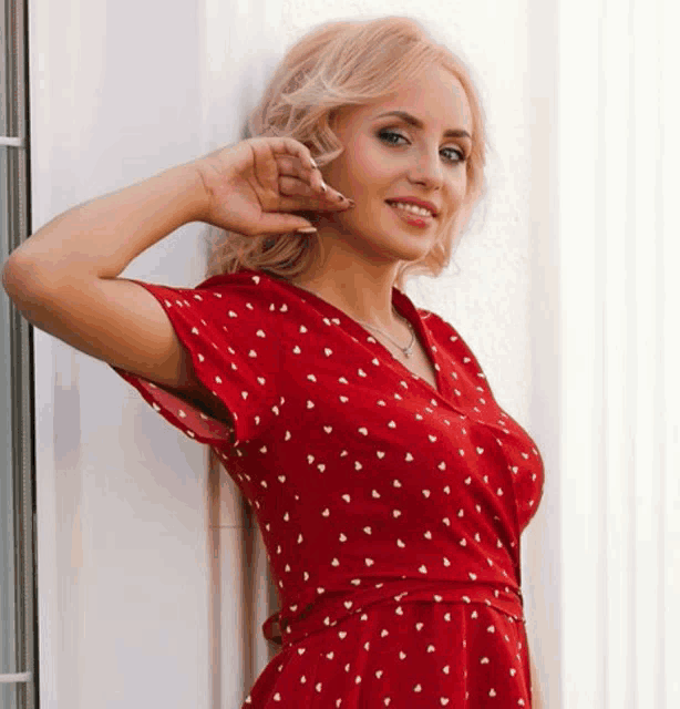 a woman in a red dress with white hearts on it is smiling