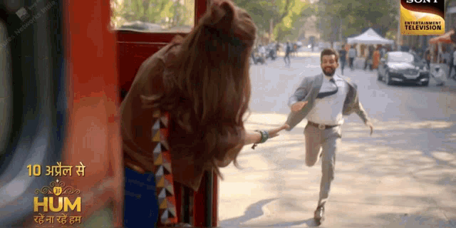 a man in a suit is running towards a woman holding her hand
