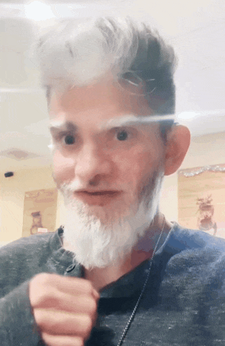a man with gray hair and a white beard is looking at the camera