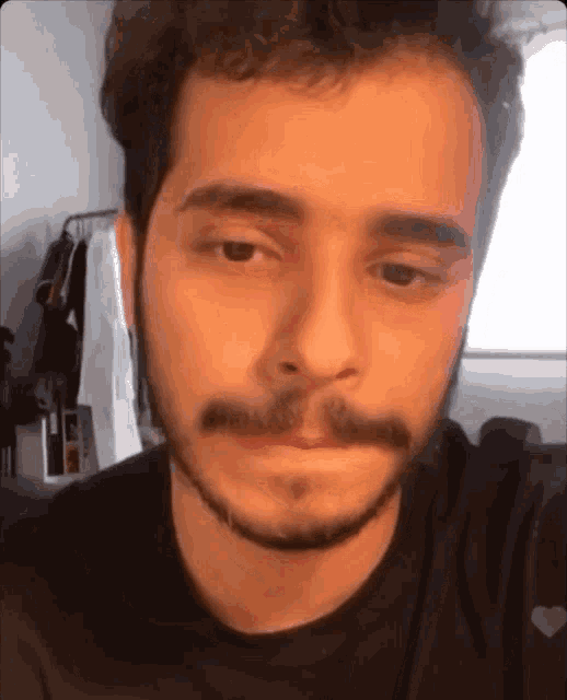 a man with a beard is wearing a black shirt with a heart on the front