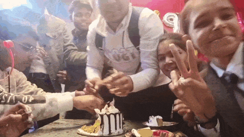 a group of people are celebrating a birthday with a cake that has the number 50 on it