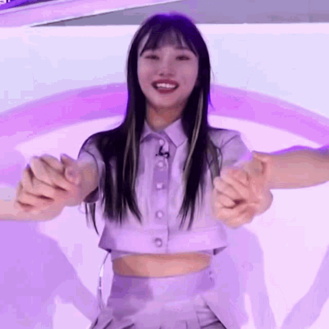 a girl in a purple crop top and skirt is holding someone 's hand .