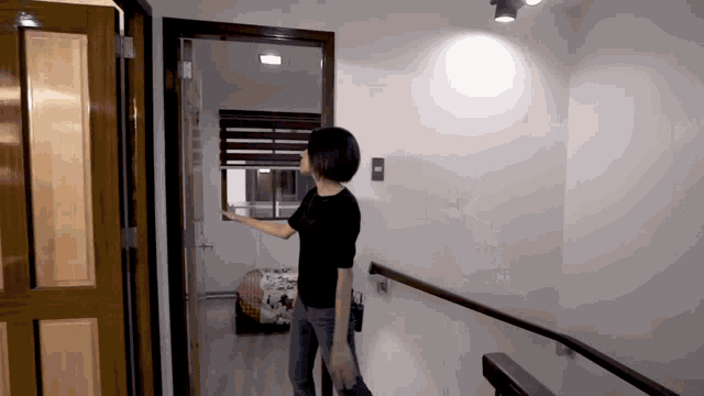 a woman in a black shirt is opening a door