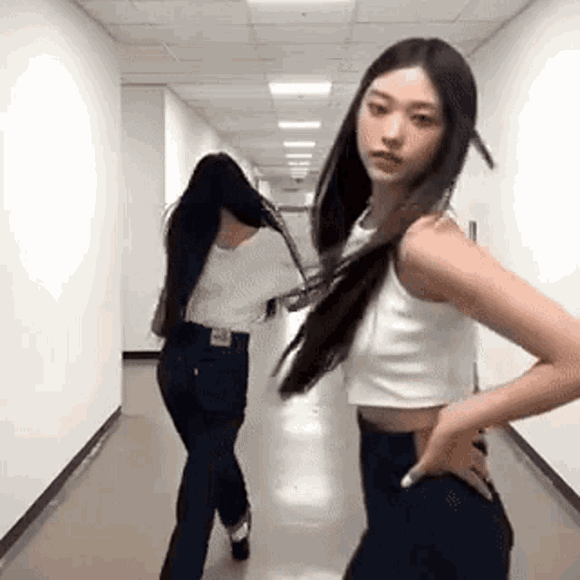 two women are standing next to each other in a hallway and dancing .