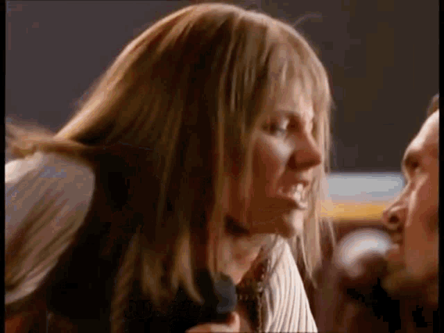 a woman with long hair is holding a microphone in front of a man 's face .