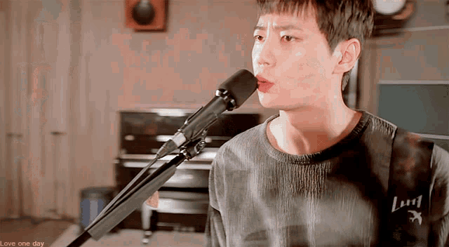 a man singing into a microphone with the words love one day on the bottom right