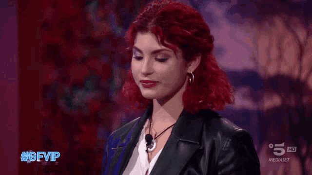 a woman with red hair is smiling in front of a sign that says 5 hd