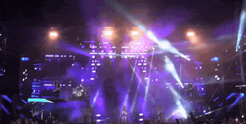 a group of people on stage with purple lights behind them