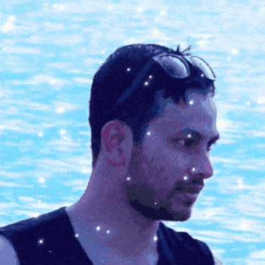 a man wearing sunglasses stands in front of a blue water surface