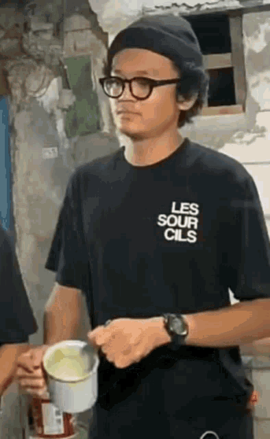 a man wearing a black shirt that says les sour cils on it